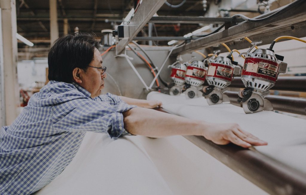 Person holding fabric on a large cutting machine