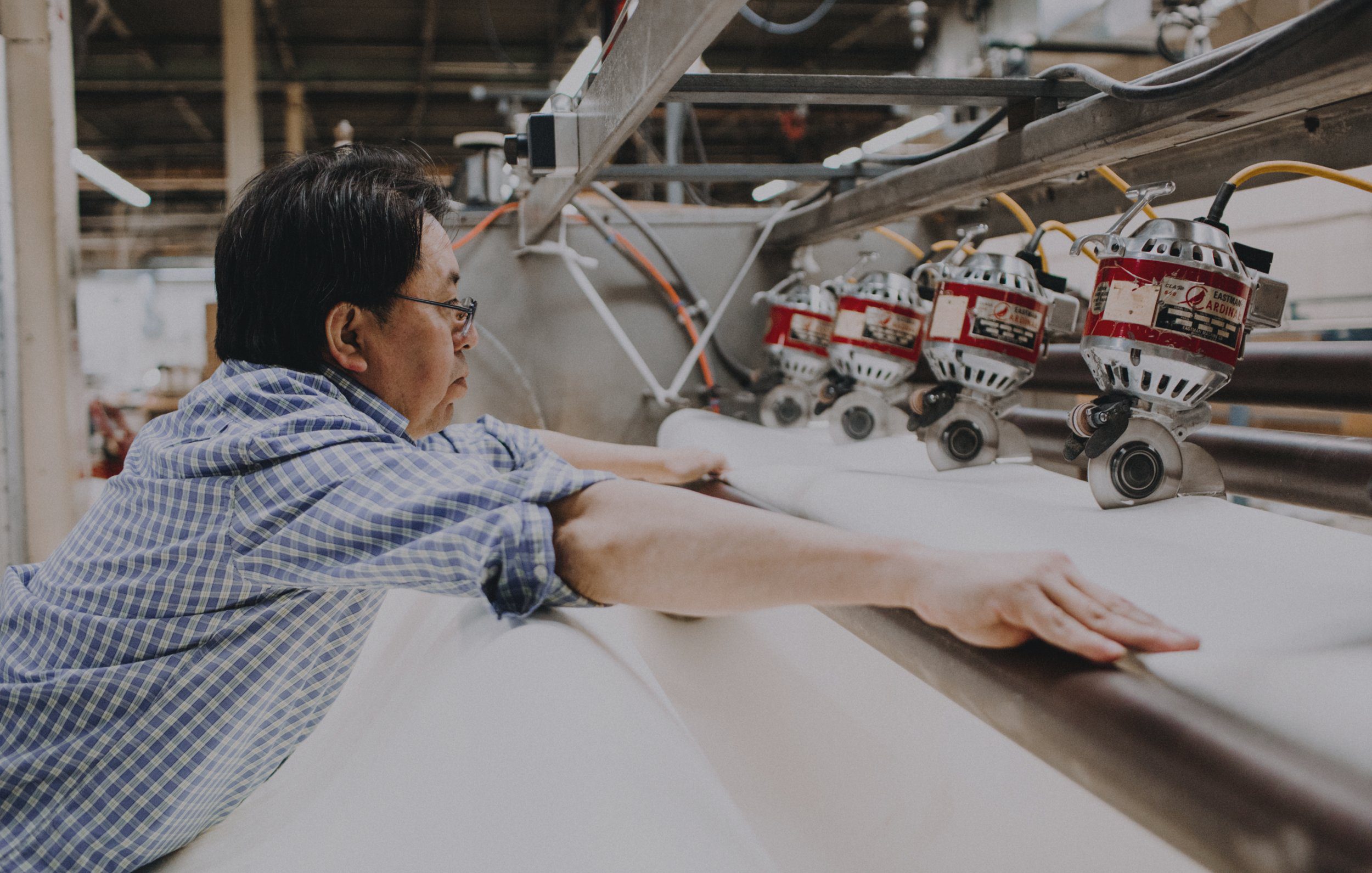 Person holding fabric on a large cutting machine