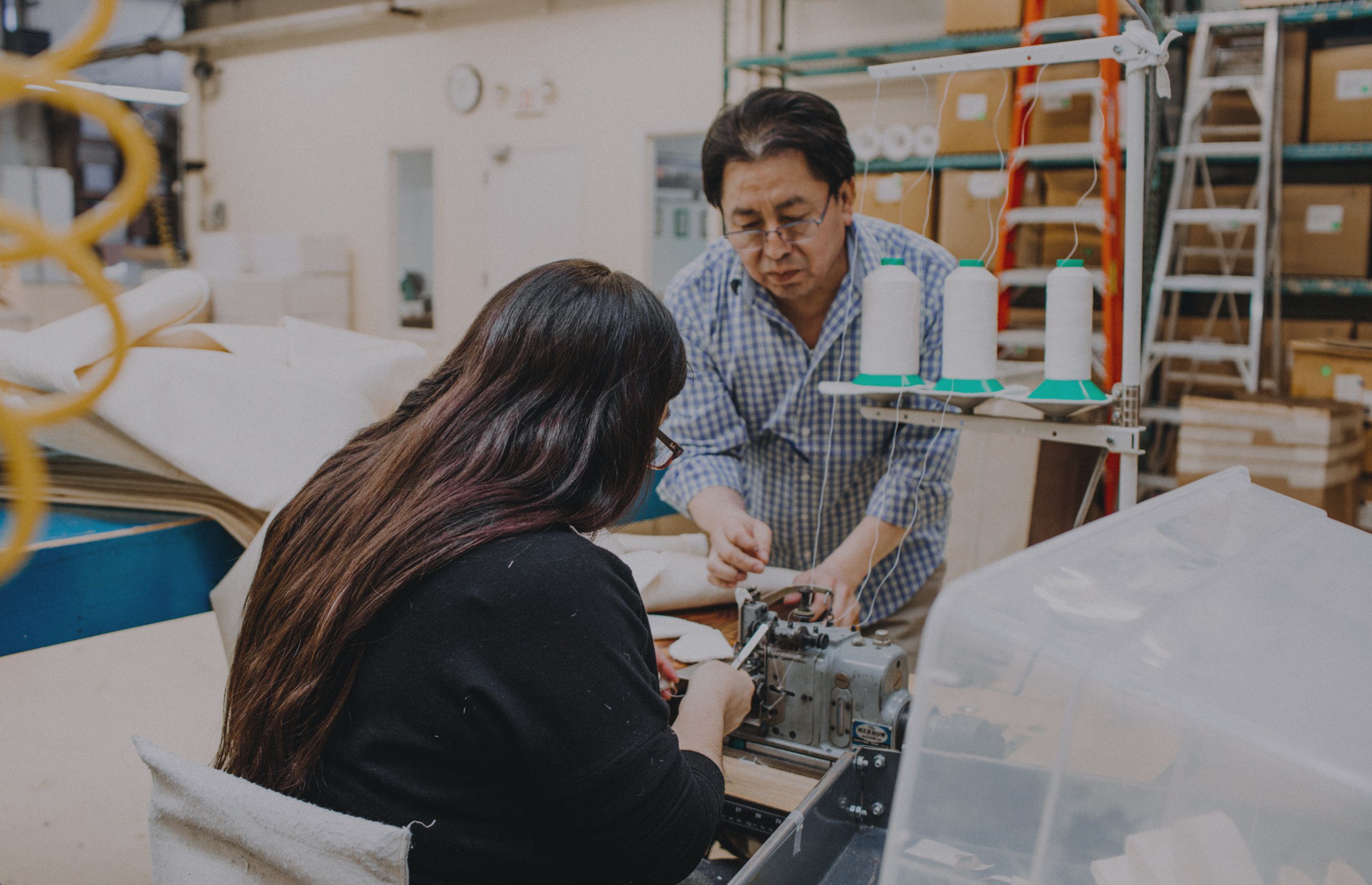 Two people working on a sewing machine
