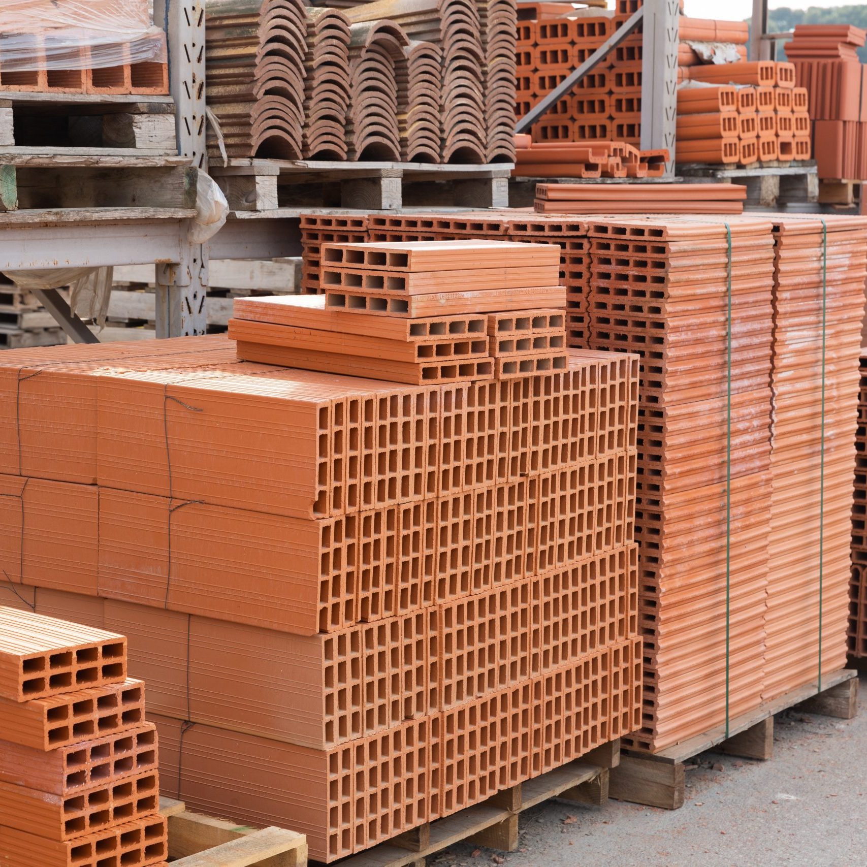 Pallets with stack of redbricks lying at warehouse Large pile of bricks